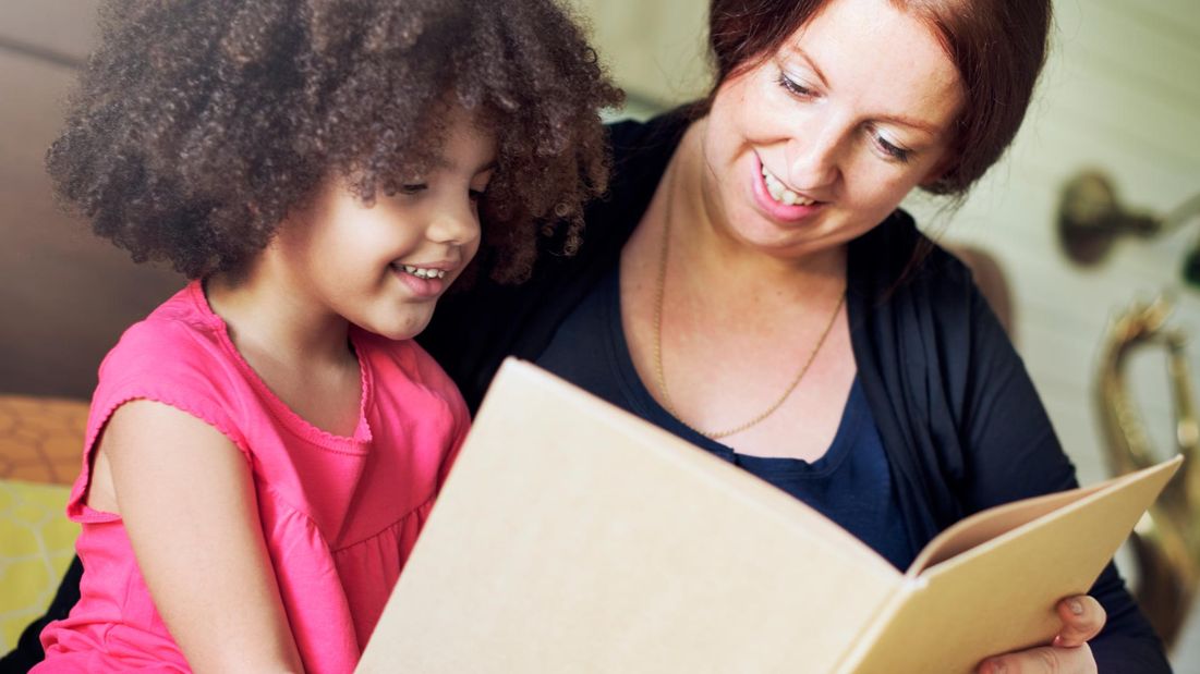 A young girl reading with a speech therapist