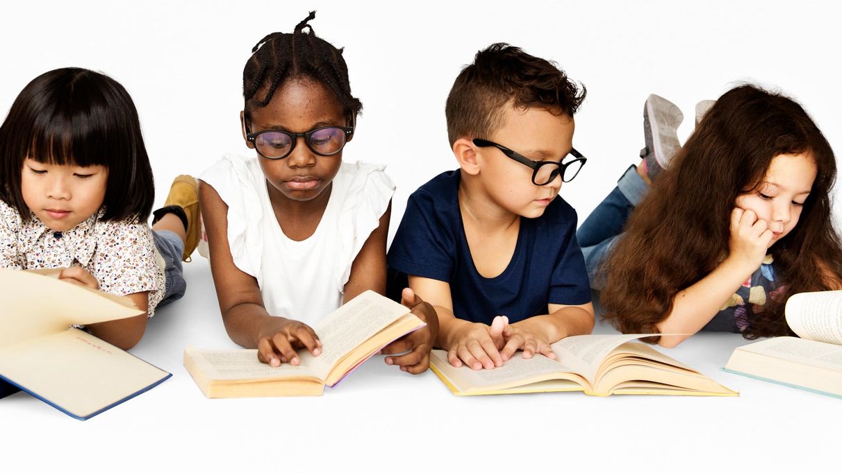 A group of children laying on the ground reading 