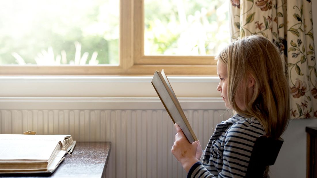 A young girl reading though a book